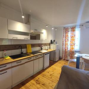 a kitchen with white cabinets and a wooden floor at Apartament Urocze miejsce in Kazimierz Dolny +17 photos