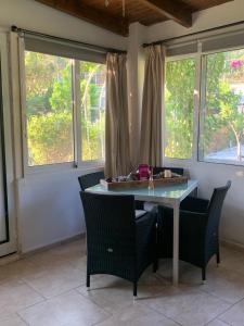 a table and chairs in a room with windows at La casa di mare in Agios Gordios
