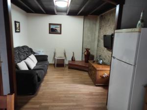 sala de estar con sofá negro y nevera en Casa de Xusto en Carnota