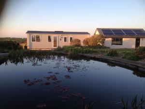 une maison avec des panneaux solaires au-dessus d'un étang dans l'établissement Golden Burn Cottage Caravan, à Padstow