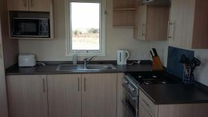 a kitchen with a sink and a microwave at Golden Burn Cottage Caravan in Padstow