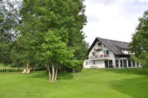une grande maison blanche avec un arbre dans la cour dans l'établissement Apartments Bledea, à Bled