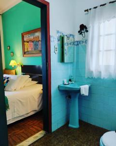y baño con cama, lavabo y ducha. en Pousada Vila Inconfidentes - Centro Historico en Tiradentes