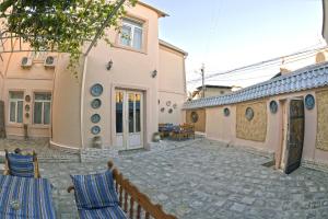 ein Haus mit einem steinernen Innenhof mit Stühlen davor in der Unterkunft Minzifa Inn in Buxoro