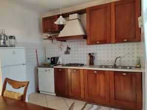 cocina con armarios de madera y nevera blanca en Villa Lucia Anna, en Scalo dei Saraceni Manfredonia