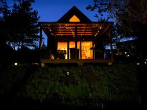 a small house in the middle of a yard at night at Cosy Cabin - domek na Kaszubach z sauną, balią i basenem in Stara Sikorska Huta