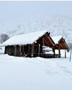 una cabaña de madera con nieve encima en Camping Cajupi, en Gjirokastra