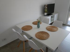 uma mesa de jantar branca com cadeiras e uma televisão em Appartement Baumgärtner em Naturno