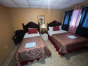 a hotel room with two beds with red pillows at Hotel Maya Copan Guamilito in San Pedro Sula