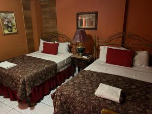 a hotel room with two beds and a lamp at Hotel Maya Copan Guamilito in San Pedro Sula