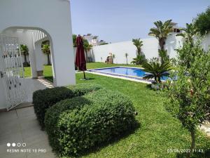 a yard with a swimming pool and some bushes at La superbe villa à Kélibia la blanche in Kelibia