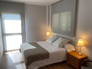 um quarto com uma cama com 2 candeeiros e 2 janelas em La Portella em Pauls de Flamisells