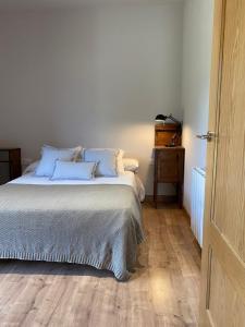 um quarto com uma cama com almofadas azuis e piso em madeira em La Portella em Pauls de Flamisells
