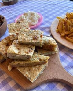 a pile of crackers on a wooden cutting board with fries at Camping Cajupi in Gjirokastër