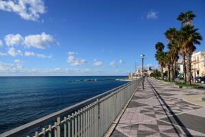 a sidewalk next to the ocean with palm trees at B&B Lungomare Diamante in Diamante