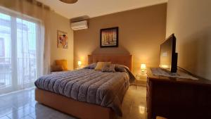 a bedroom with a bed and a desk with a television at Casa Vacanze La Melagrana in Modica