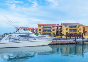 una barca bianca attraccata di fronte ad alcuni edifici di Palapa Beach Resort Curacao a Jan Thiel