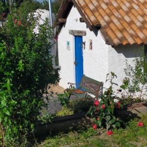 un banco frente a una casa con una puerta azul en Vivienda Rural La choza, en Jerez de la Frontera