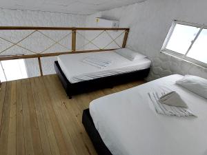 two twin beds in a room with two windows at Hotel Cabaña Playa DanRay in Coveñas