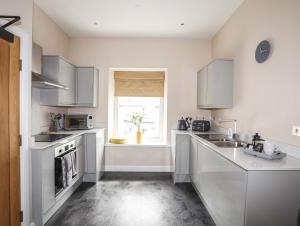 a kitchen with white cabinets and a sink and a window at Moel Tryfan in Caernarfon