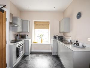 a kitchen with white cabinets and a sink and a window at Moel Tryfan in Caernarfon