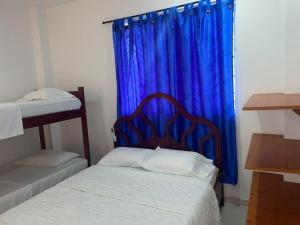 1 dormitorio con 2 camas y cortina azul en Habitacion Playa Linda 102, en Coveñas