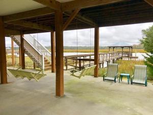 eine Veranda mit zwei Stühlen und einem Tisch und einem Dock in der Unterkunft Watercolors in Edisto Island + 9 Fotos