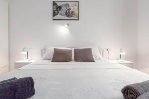 białe łóżko w białej sypialni z 2 lampami w obiekcie Bora Apartment Pula w Puli