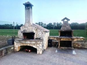 a stone fireplace with two ovens in a field at Villa Pedrosu in Casa Linari