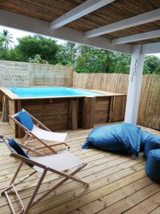 eine Terrasse mit einem Pool, 2 Stühlen und einem Tisch in der Unterkunft Cottage Tropical in L’Étang-Salé