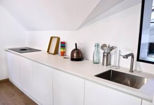 uma cozinha branca com um lavatório e uma bancada em Margarita Apt Climatisé T2 4 pers Centre parking em Le Touquet-Paris-Plage