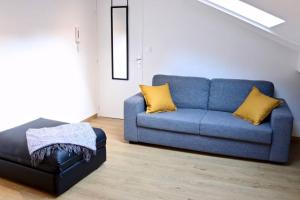 um sofá azul com duas almofadas amarelas numa sala de estar em Margarita Apt Climatisé T2 4 pers Centre parking em Le Touquet-Paris-Plage