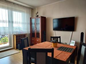 a dining room with a table and a flat screen tv at Cozy Rooms Gdańsk in Gdańsk