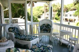 a screened porch with wicker chairs and tables andupholstery at Jumangi in Edisto Island