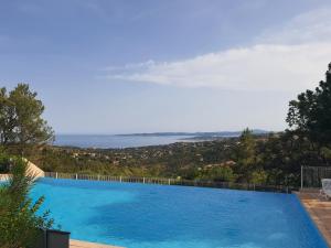 een groot zwembad met uitzicht op de oceaan bij Appartement vue mer Golfe de Saint-Tropez in Les Issambres