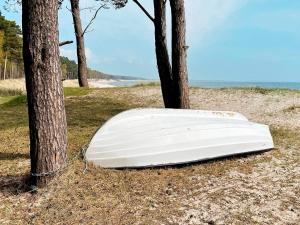 a white boat tied to a tree on the beach at 4 person holiday home in YSTAD in Ystad