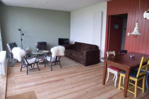 a living room with a couch and a table and chairs at Huisje onder de Linden in Munnekeburen