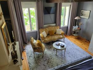 ein Wohnzimmer mit Sofa, Stühlen und einem Tisch in der Unterkunft Chambre Bordeaux, piscine et spa in Lugon et l’Ile du Carney