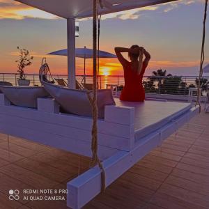 una mujer sentada en los escalones viendo la puesta de sol en Residence Porto Ulisse, en Parghelia