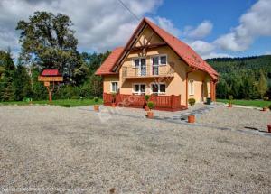 a house with a red roof on a gravel driveway at Jasionka 2 in Ustrzyki Dolne