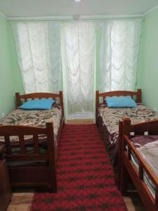a bedroom with two beds and a red carpet at Novus Navis Бричмулла in Yangiobod