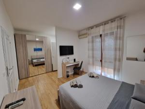una camera con letto, scrivania e TV di The Shell Guest House ad Alghero