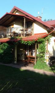ein Haus mit einer Terrasse mit einer Bank davor in der Unterkunft Willa Sara II in Okuninka