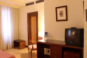 una camera d'albergo con TV su un comò in legno di Hotel Monterrey a Salamanca