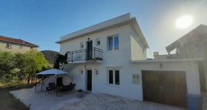 a white house with a balcony and an umbrella at sunny holiday in Vinišće