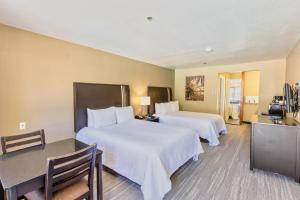 a hotel room with two beds and a table and chairs at The Oakhurst Inn at Yosemite in Oakhurst