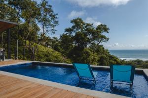 2 sillas sentadas junto a una piscina con el océano en Le Suite, en Santa Teresa Beach