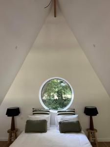 1 dormitorio con 1 cama y ventana redonda en La Maison Villeneuve - Lodges avec bains nordiques, en Donnay