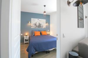 sypialnia z niebieskim łóżkiem z pomarańczowymi poduszkami w obiekcie Le Rétro, T2 hypercentre chic et cosy, Wifi par SOVALFI w mieście Saint-Étienne