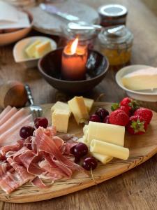 un piatto di alimenti con formaggio di carne e frutta e una candela di Dobbeltværelse i smuk palævilla a Stenstrup